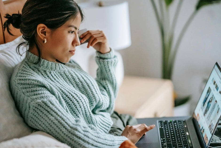 A young woman using a laptop for online shopping and leaving a review.