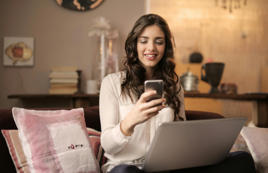 A woman using a phone and a laptop simultaneously