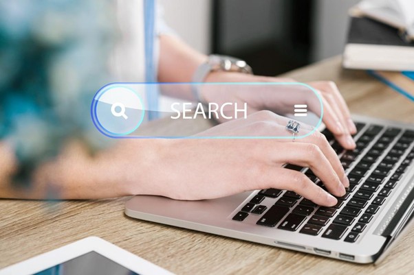 A close-up of hands typing on a laptop with a digital search bar overlay, representing the execution of a keyword-focused content strategy.